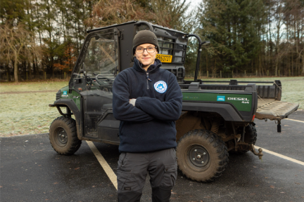 Young woman wearing glasses in front of a 4 wheel drive vechicle.